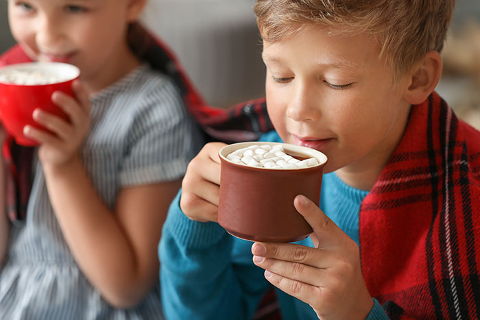 boy and girl drinking hot chocolate with red flannel blanket