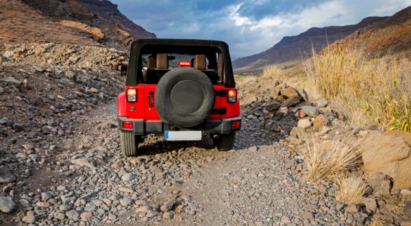 A red jeep on sandy beach and beuatiful blue sunny sky view in summer time. red jeep driving in desert